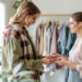 une-styliste-de-mode-discute-des-tendances-avec-un-client-dans-une-boutique-elegante-entouree-de-vetements-et-daccessoires
