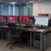 Salle de supervision moderne d’une agence web, avec plusieurs écrans montrant des interfaces abstraites d’alerte de sécurité et de maintenance, dans une ambiance professionnelle aux lumières bleues et rouges.
